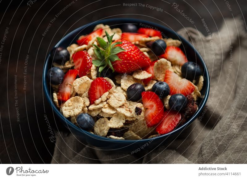 Fresh cornflakes served with strawberries and blueberries placed on wooden table breakfast strawberry blueberry cereal delicious fresh bowl organic healthy