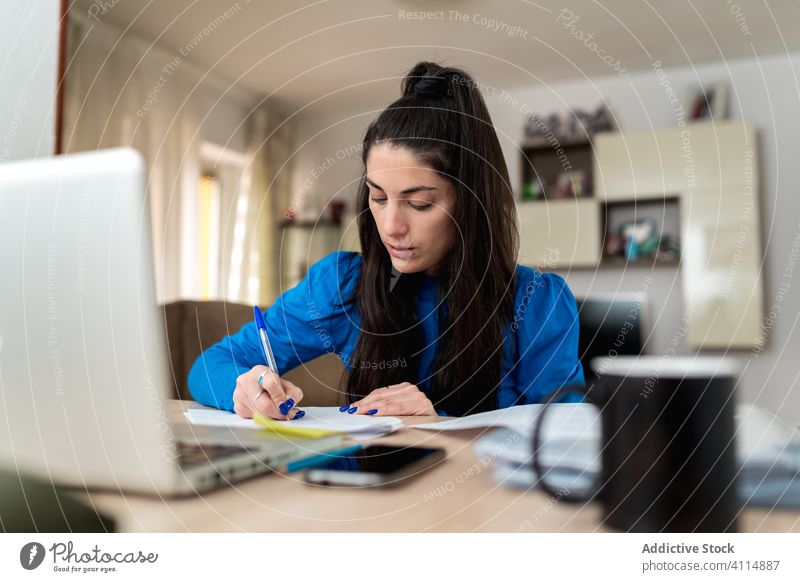 Female freelancer working at home woman write note paper focus project remote female laptop table job cozy room gadget device concentrate business document