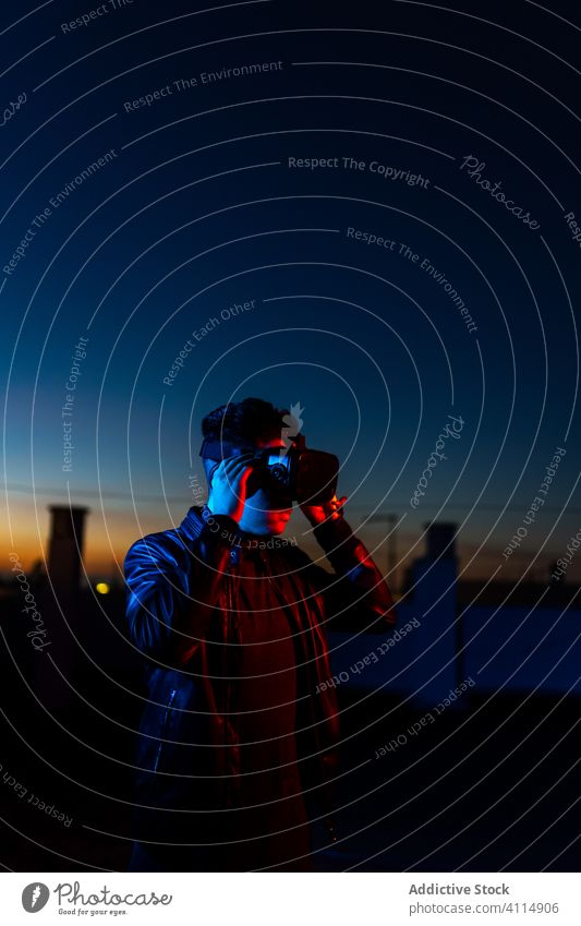 Young man exploring virtual reality night vr dark street headset goggles futuristic illuminate neon red light male modern device gadget 3d sky technology