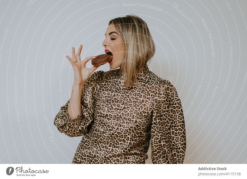 Cheerful stylish woman eating donuts smile style model bite closes eyes female fashion trendy dress leopard print doughnut dessert pastry tasty chocolate food
