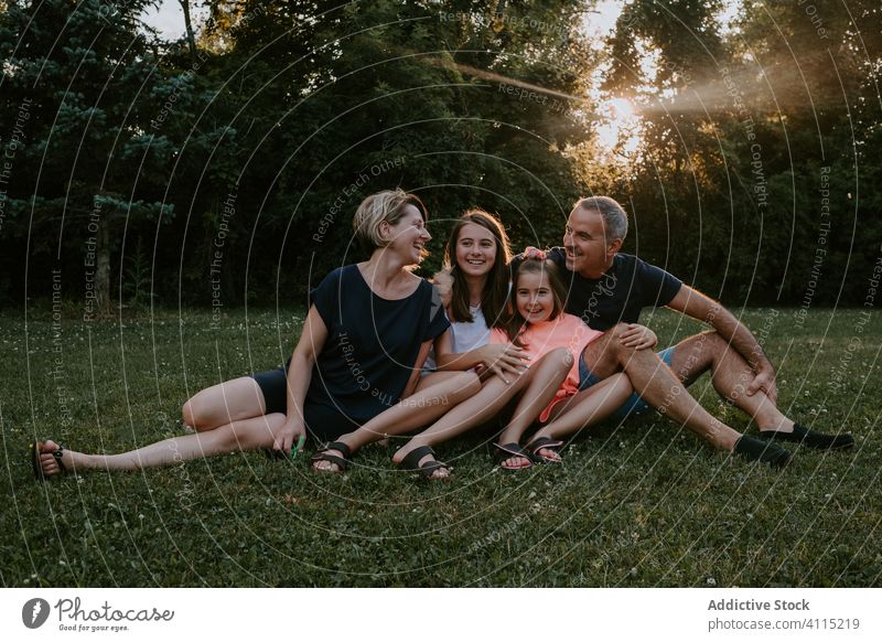 Happy family resting on green meadow together nature relax sit park forest countryside summer smile active casual grass love relationship lifestyle tree bonding
