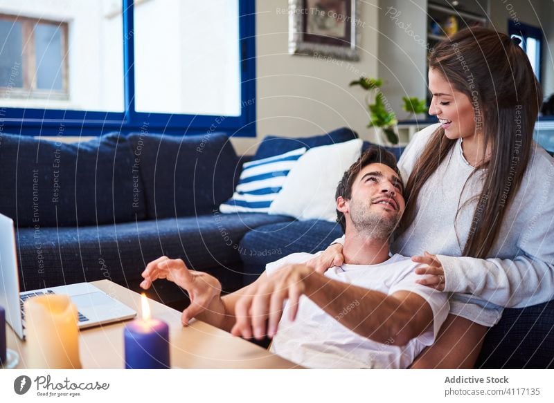 Young couple in love resting together at home hug relationship romantic casual sofa relax young positive happy cozy embrace smile lifestyle affection