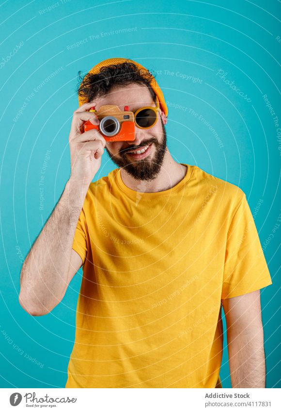 Cheerful bearded man taking photos take photo smile photo camera style modern summer colorful bright happy male hipster trendy outfit small toy gadget device