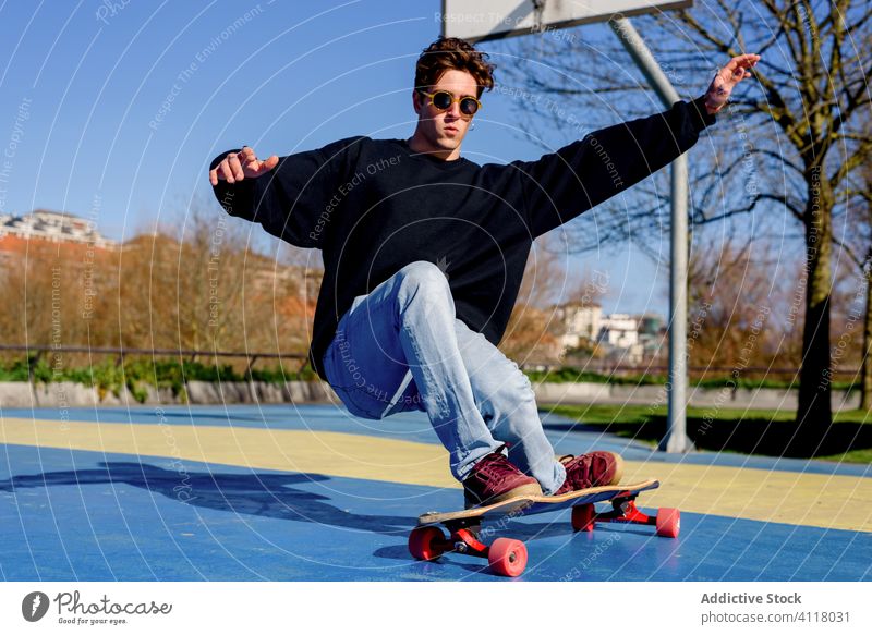 Young man falling from skateboard ride trick sports ground hipster arm raised urban city male skater street energy hobby sunny modern activity practice