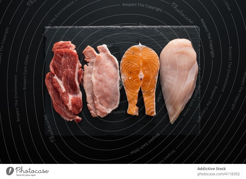 Flat lay of various types of protein rich meat on cutting board product fillet beef fish chicken pork food healthy assorted meal raw nutrition fresh organic