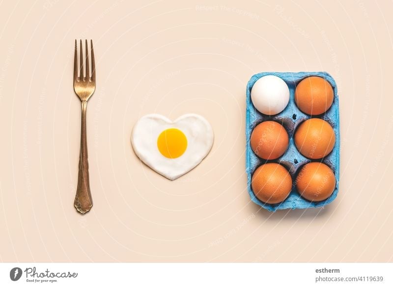 Top view of chicken eggs in an open blue cardboard box with a vintage fork and a heart-shaped fried egg easter eggs fresh egg yolk eat container love basket