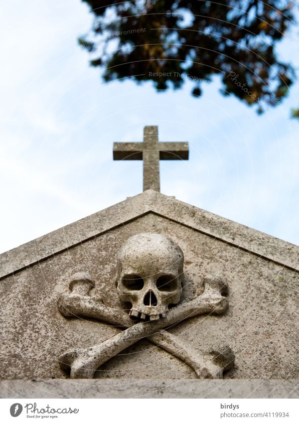 Christian cross with a skull underneath in a cemetery , frog perspective Crucifix Death pass away Cemetery Grave Religion and faith symbolism Climate change