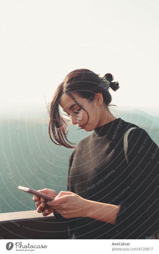 Young woman checking his phone in a mountain during a sunny day people communication portrait technology model professional smile business face happy home light