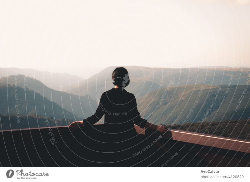 A young woman in front of massive mountains looking to the horizon during a sunny day wellness and liberty concept white copy-space 20s 30s earth enjoyment