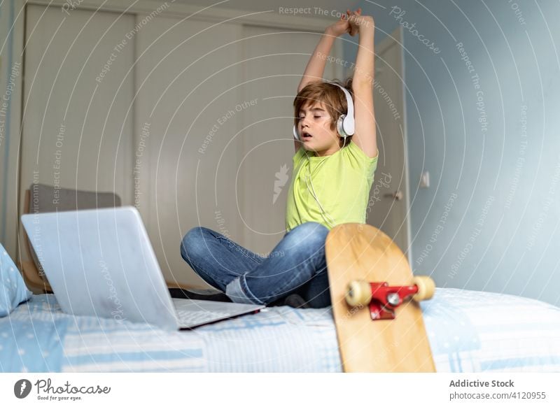 Tired kid browsing laptop at home sad using bored depress quarantine bed boy internet device casual online gadget connection lifestyle surfing modern bedroom