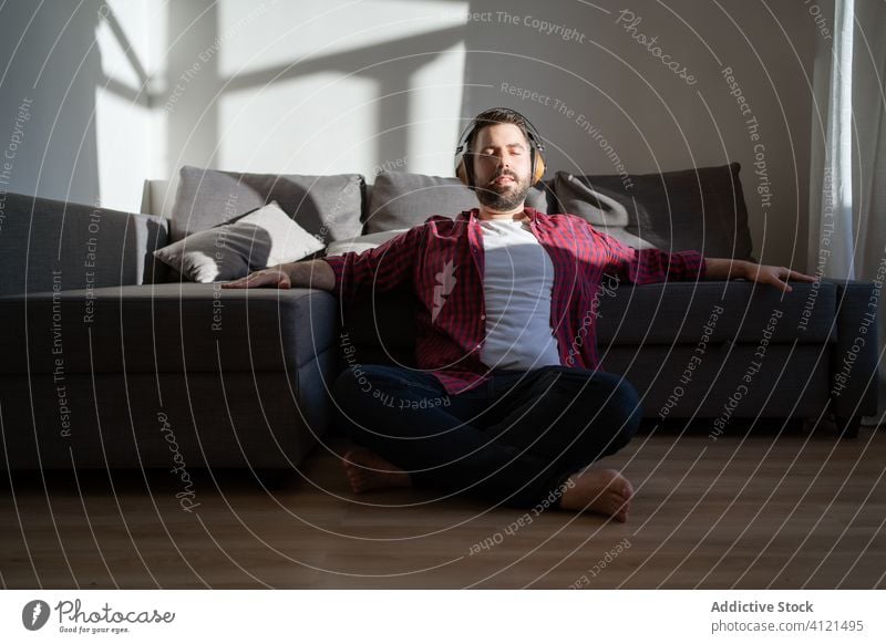 Young man listening to music at home young leisure casual headphones technology caucasian adult lifestyle happy sofa person relaxation modern room indoors