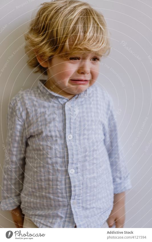 Sad boy crying in modern studio disappoint little child weep sad naughty whine kid casual childhood face expression adorable cute shirt apparel outfit wear