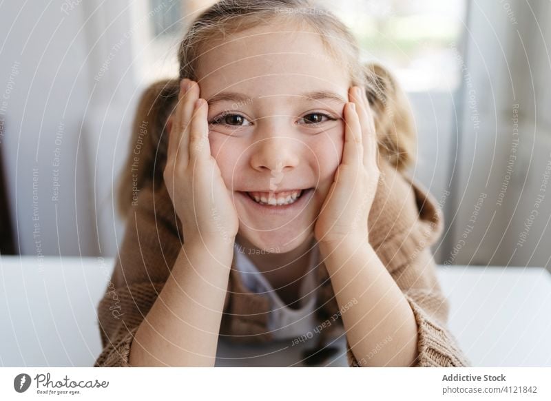 Happy little girl looking at camera in cozy home happy smile kindergarten kid lean on hand child charming portrait cute childhood adorable education joy