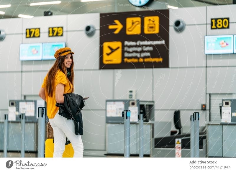 Cheerful young woman saying goodbye before leaving at airport check in travel farewell colorful departure leave joy trendy luggage bag counter passport carry