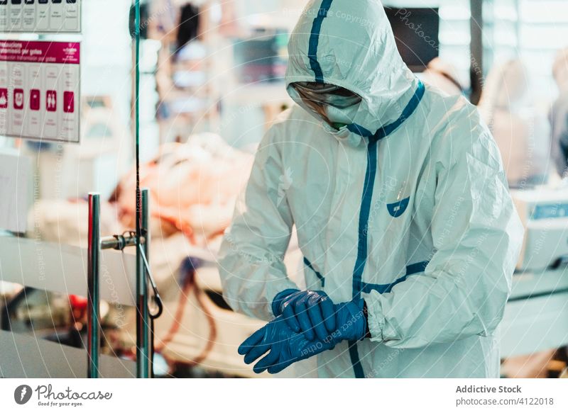 Doctor in protective uniform putting on gloves in clinic doctor mask latex surgery hospital specialist sterile health care treat white work put on practitioner