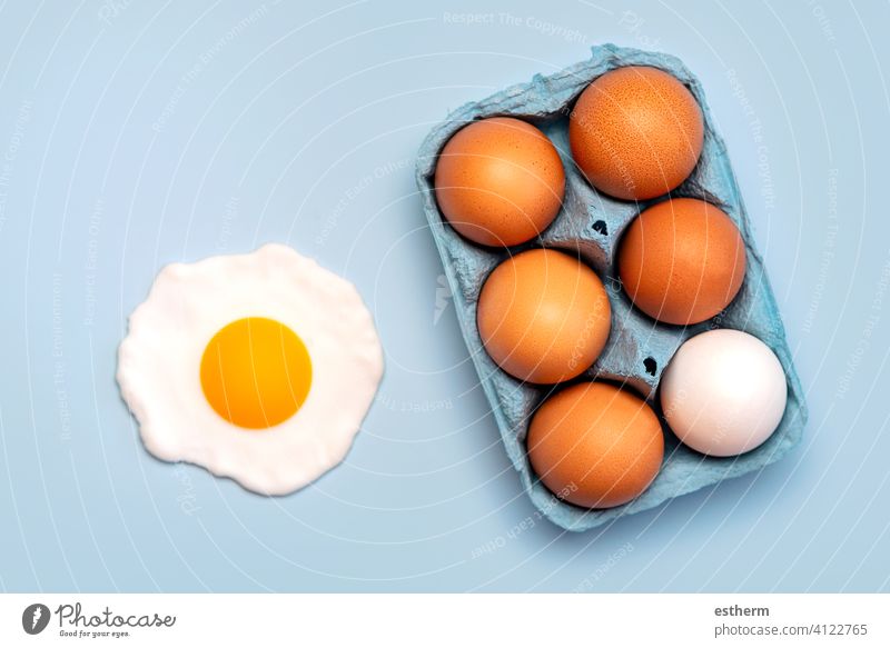 Top view of chicken eggs in an open blue cardboard box and a fried egg easter eggs fresh egg yolk eat container basket farming storage farmyard animal egg