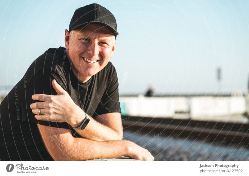Outdoor portrait of smiling man in his 40s outdoor positive smile sunny cap jockey cap looking at camera copy space joy human healthy mid middle-aged relaxed