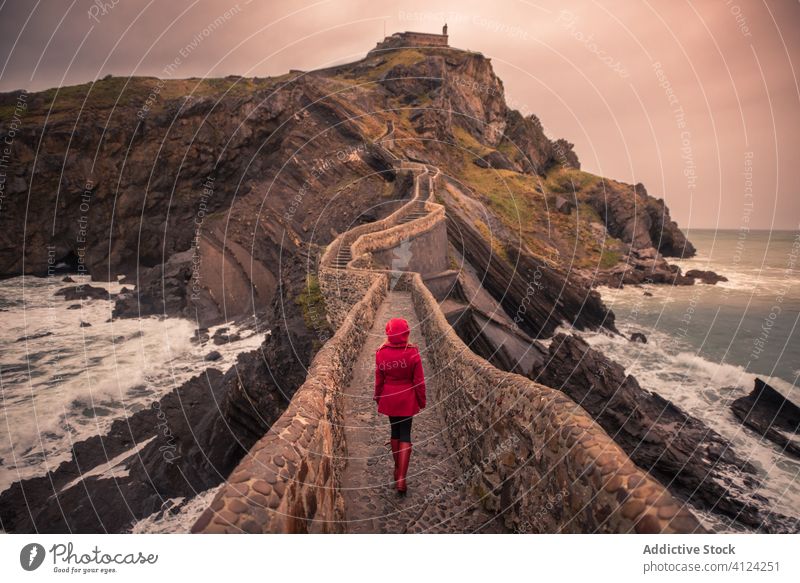 Woman walking on stone bridge surrounded by sea in Basque Country tourist woman seashore spain warm travel explore island trip journey vacation tourism holiday