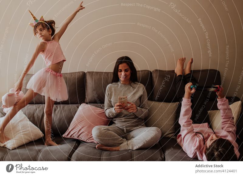 Mother and children chilling on sofa mother home dance smartphone using play video game woman kid son daughter girl teen parent together browsing gadget device