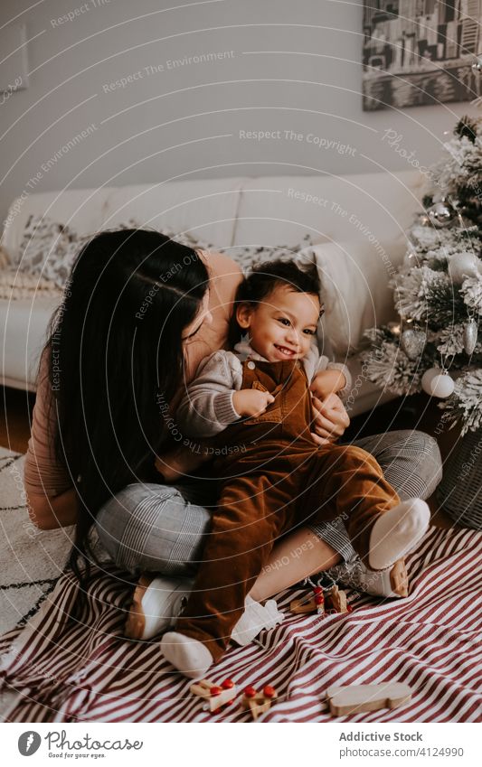 Cheerful loving mother hugging little son sitting on floor near Christmas tree cuddle christmas home playful cozy holiday smile child together kid parent