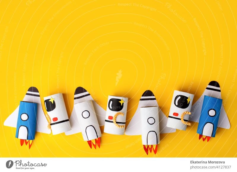 School kindergarten crafts, paper spaceship, shuttle, astronaut on yellow background with copy space for text. Party, start up launch concept, diy, creative idea from toilet tube, recycle