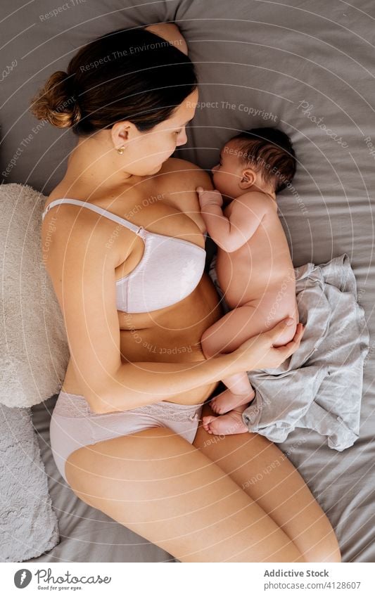 Mother breastfeeding little baby on bed woman mother love care home comfort cozy child underwear lingerie peaceful lying together cute young motherhood