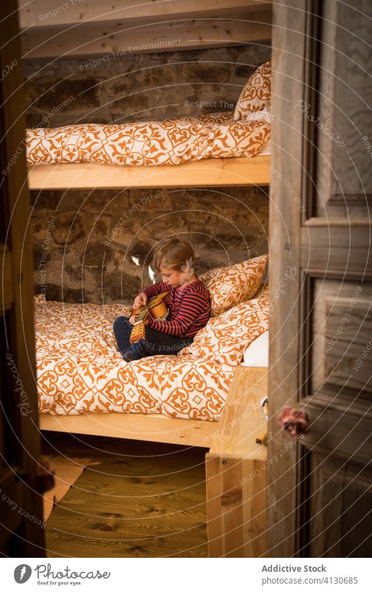 Calm boy playing guitar on bed ukulele child chill comfort having fun hobby cantabria spain kid childhood casual outfit sit relax rest concentrate focus calm