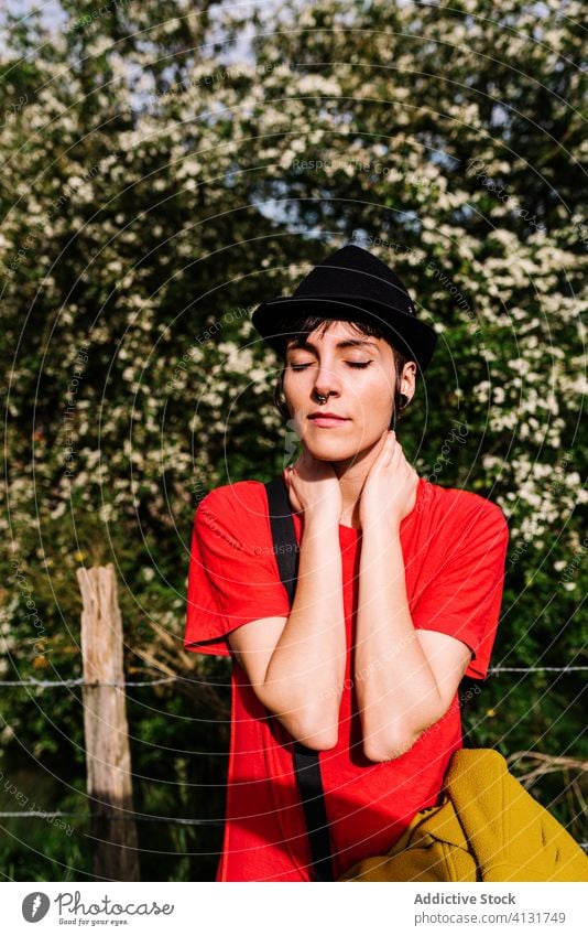Tranquil woman enjoying sun in countryside tranquil serene informal sunny rural nature female asturias spain relax calm trendy androgynous alternative peaceful