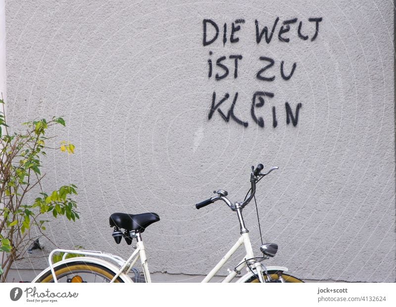 The world is too small Plaster Wall (building) Spray German saying Street art Daub Bicycle Parking area shrub Ladies bike Figure of speech Authentic Coincidence