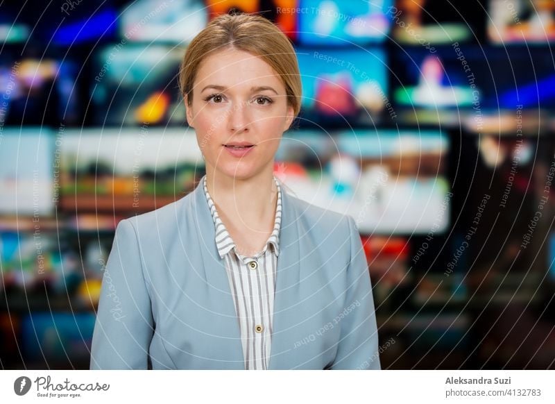 An anchorwoman reporting live breaking news sitting in Tv studio. Background of multiple screens of broadcast control room. Journalism concept announcement