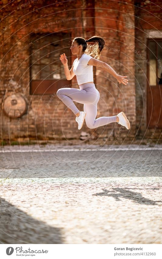 Young woman juping high during training in the urban environment city young fit fitness female jump athlete workout sport athletic activity caucasian exercise