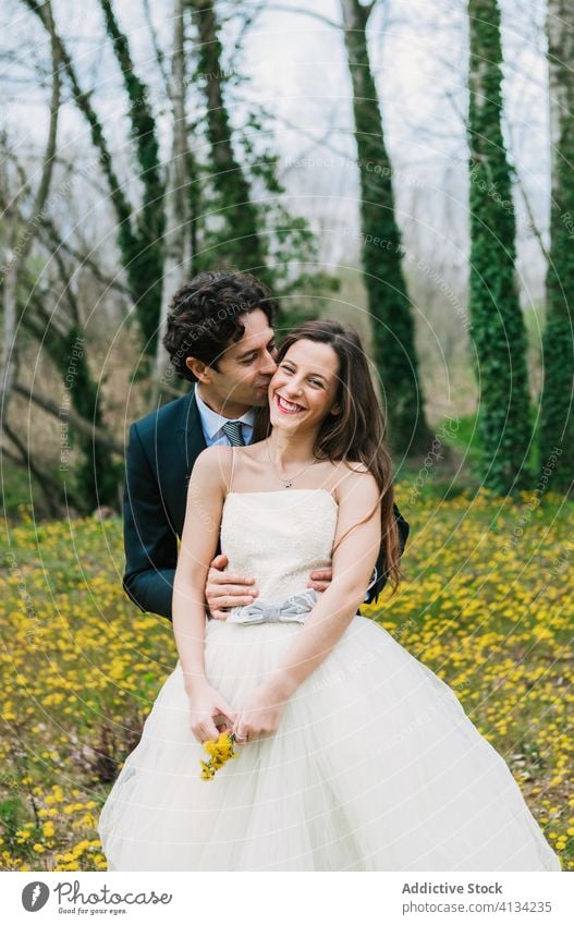 Cheerful newlyweds on meadow with flowers hug couple wedding bride groom wedding day cheerful bloom smile classy dress suit handsome romantic together love