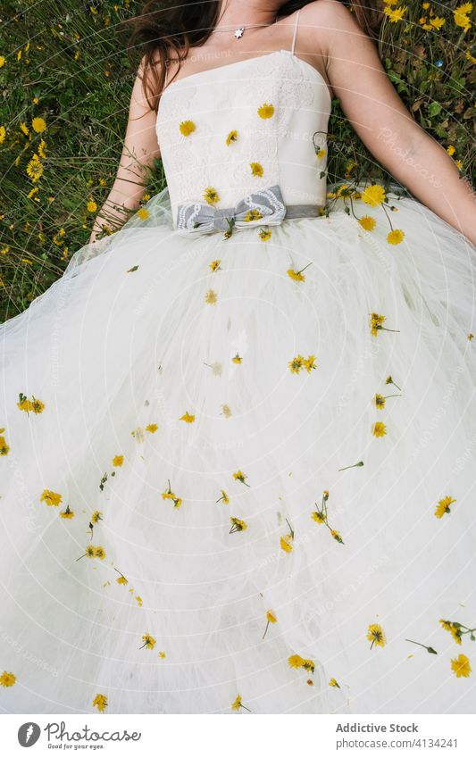 Crop bride in meadow with dandelions newlywed wedding day flower wedding dress high heels bloom female field blossom relax lawn calm tranquil serene sit