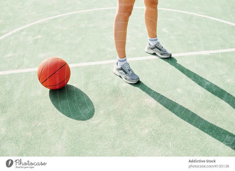 Sportswoman with basketball ball standing on court leg sports ground training game player prepare line mark female workout activity wellbeing energy practice