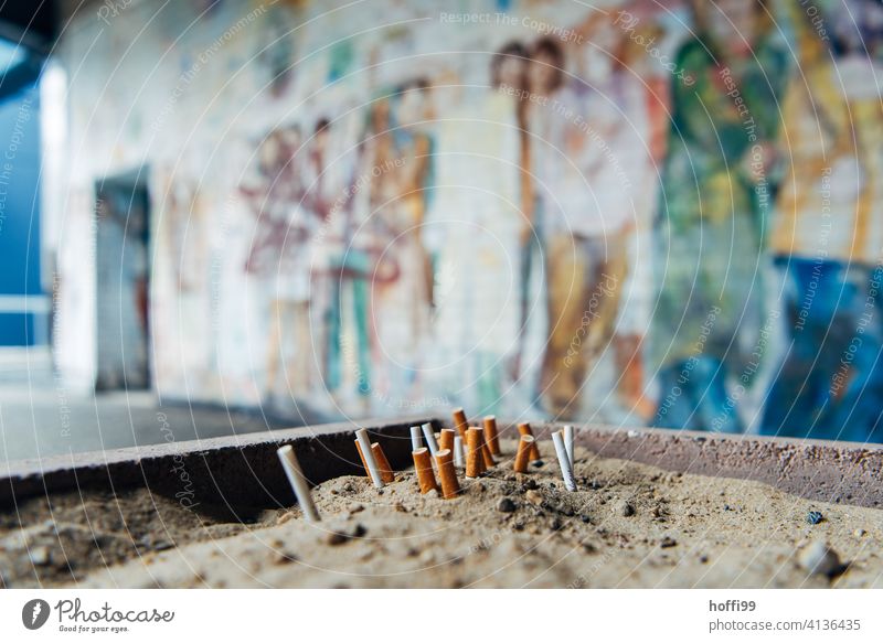 squeezed out butts in the sand in front of painted wall Cigarette Butt Smoking Tobacco products Filter-tipped cigarette Ashes tilt Unhealthy Smoke Ashtray