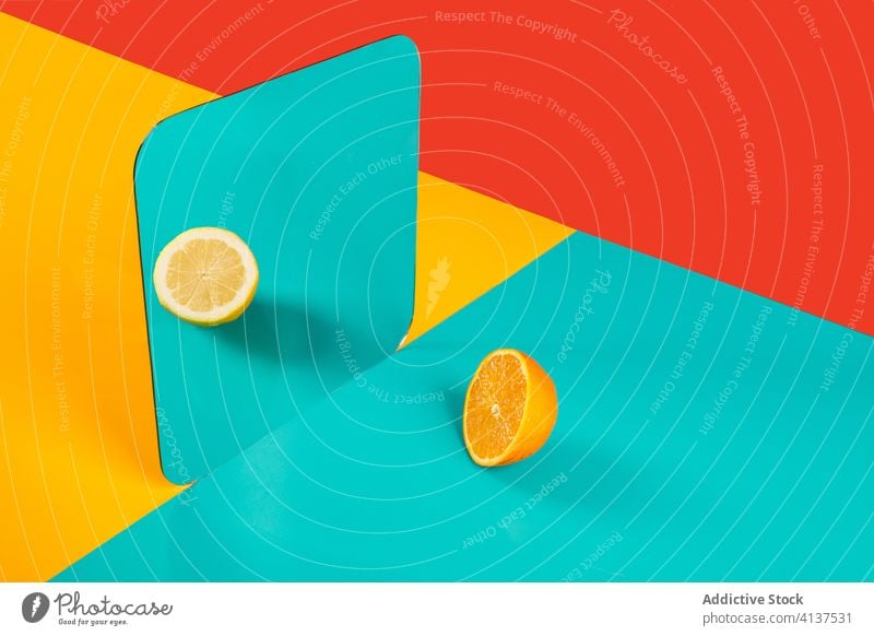 Vivid multicolored backdrop with halves of fresh citrus fruits vivid yellow blue reflection concept stereotype perception imagination orange lemon distortion