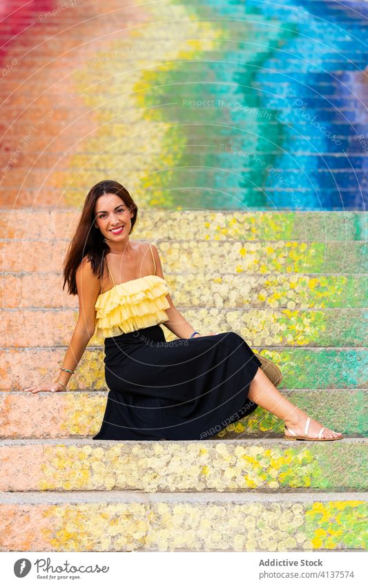 Smiling woman on colorful steps summer vacation city traveler rainbow stair street art female cheerful tourist smile sit happy delight joy tourism holiday relax