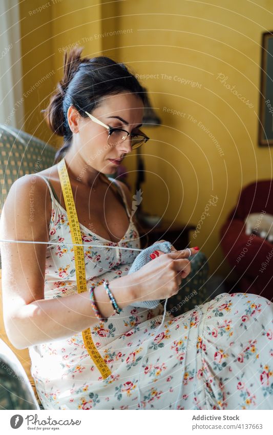 Lady sitting in armchair and knitting woman home hobby cozy focus handmade room weekend female rest relax glasses brunette comfort calm serene lifestyle