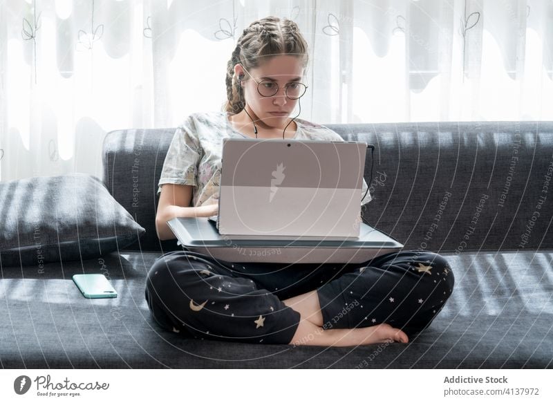 Young woman with headphones using laptop at home earphones young listen watch gadget online student casual video device internet browsing lifestyle connection