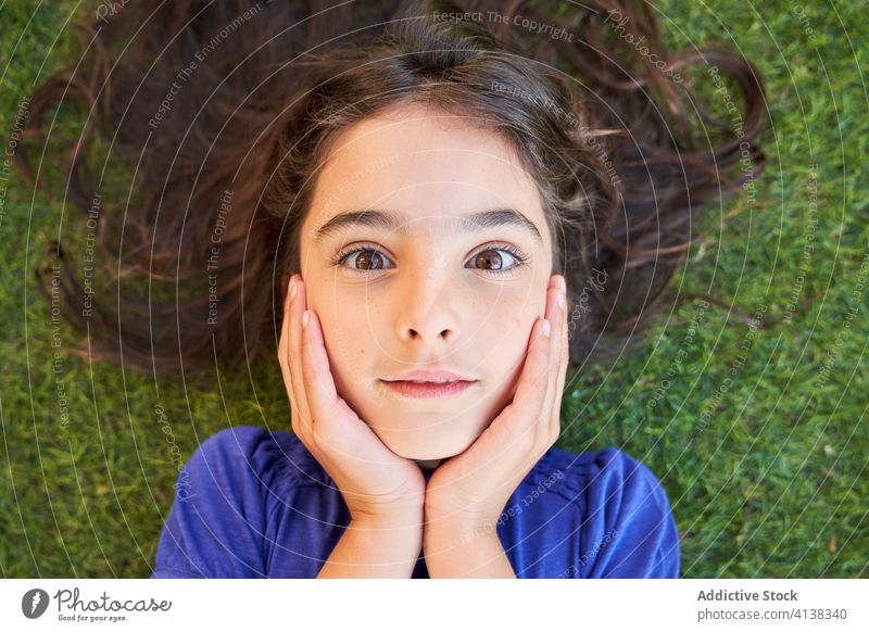 Amazed girl lying on grass and looking at camera amazed astonish kid surprise positive wow disbelief unbelievable stare preteen child female expressive