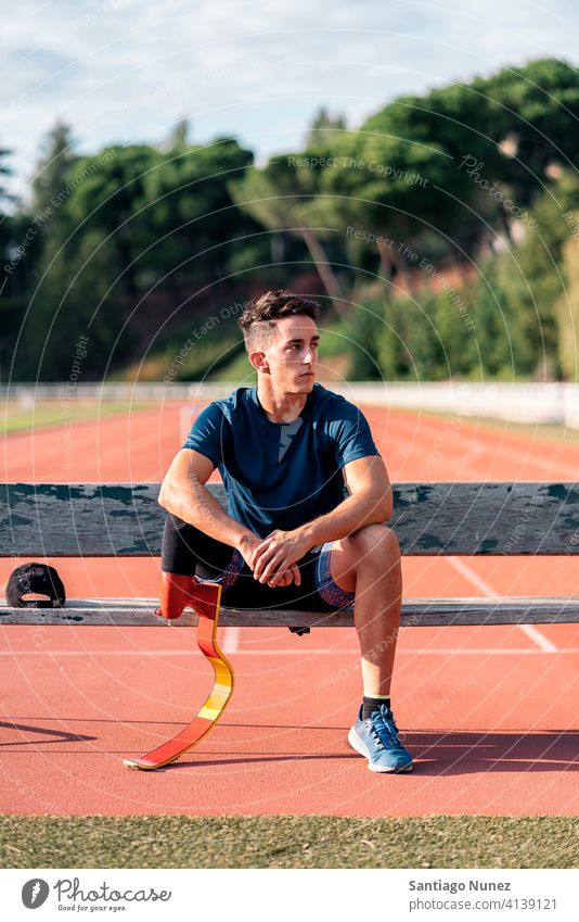 Disabled Man Athlete Resting bench sitting portrait boy looking at camera running track stadium athlete young man runner sport prosthesis prosthetic disability