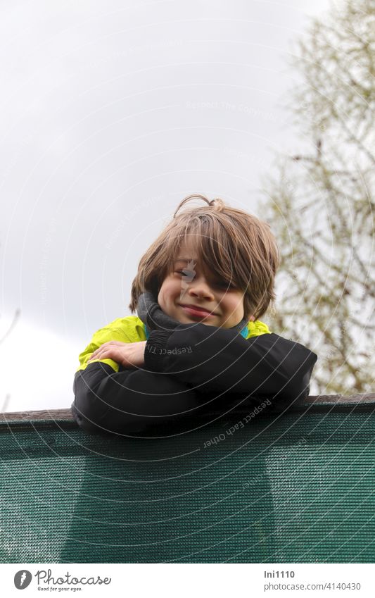 Child with folded arms looks mischievously into the camera from a climbing seat in the forest Boy (child) Impish Hunting Driven hunt buck Wood Framework