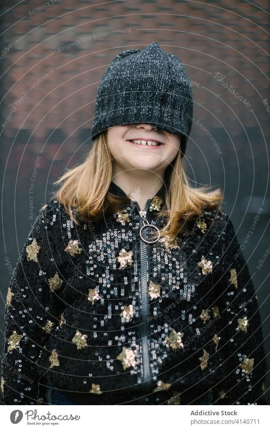 Unrecognizable smiling girl in warm cap covering half of face fun childhood warm clothes make face free time recreation lifestyle carefree positive jersey