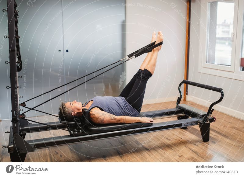 Young woman exercising on pilates reformer bed Stock Photo by sianstock