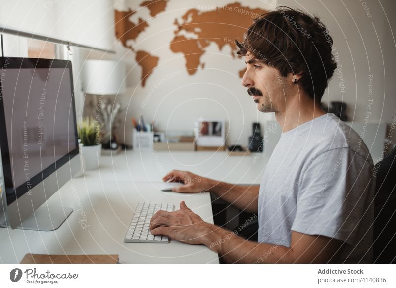 Busy male entrepreneur working on desktop computer at home project online man using keyboard typing freelance creative table workspace sit busy focus gadget