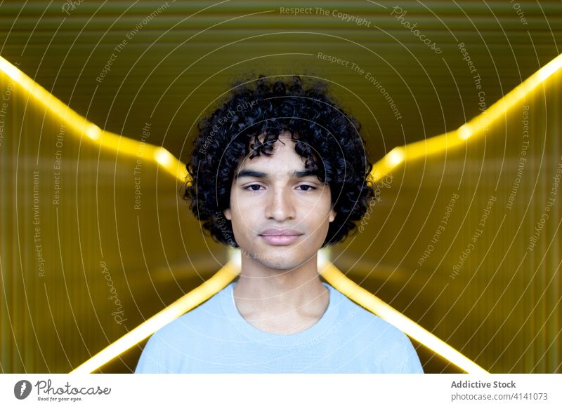Ethnic man with afro hairstyle trendy walkway illuminate city handsome calm luminous male ethnic urban modern casual confident cool street stand guy curly hair