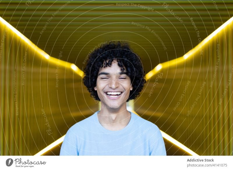 Ethnic man with afro hairstyle trendy walkway happy illuminate city handsome calm luminous male ethnic urban modern casual confident smile cool street stand