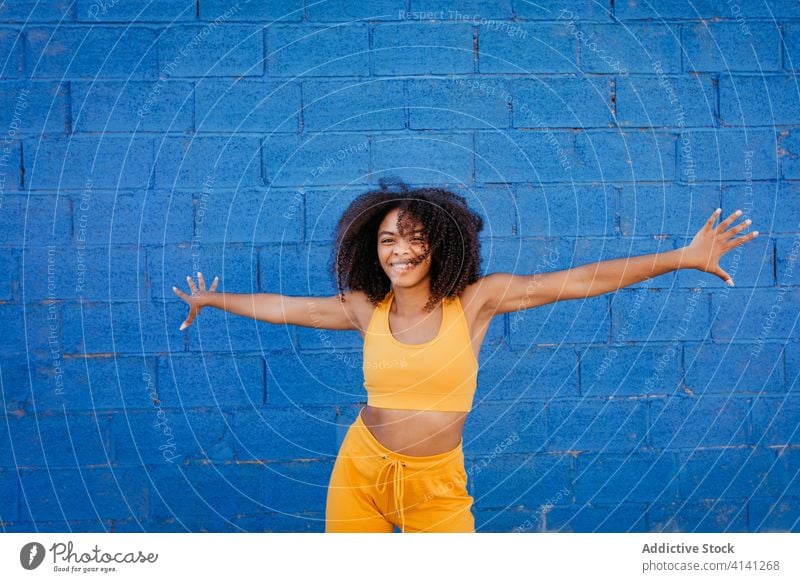 Cheerful African American woman with afro hairstyle in dancing pose dance move vivid vibrant cheerful smile motion color female black ethnic african american