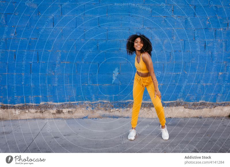 Cheerful African American woman with afro hairstyle in dancing pose dance move vivid vibrant cheerful smile motion color female black ethnic african american