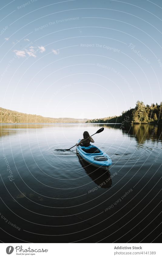 Unrecognizable woman rowing boat on river kayak travel oar silhouette cloudless national park la mauricie quebec canada trip calm lake serene tranquil rest